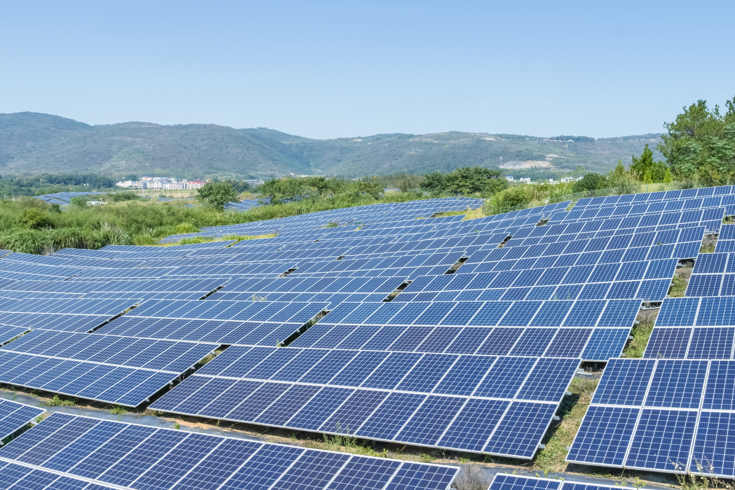 Campo de paneles solares en un paisaje montañoso, con cielo despejado y vegetación circundante, destacando la energía renovable y la sostenibilidad.
